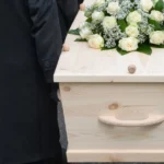 Sargträger tragen Sarg bei Bestattung zu Grabe