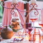 Eine festliche Tafel voller Weihnachtsdeko, Tischkerzen, schönen Tischdekorationen, goldenen und rosa Kugeln aus Glas, silbernen Kerzenhaltern und Zweigen