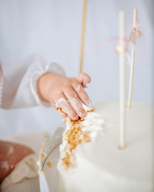 Kinderhand greift in Kuchen. Tortendeko Taufe, Babyparty, Kommunion oder Konfirmation